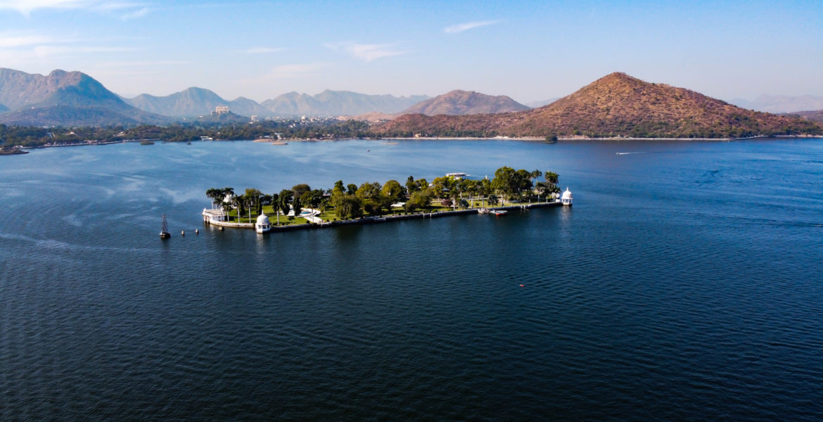 Aerial image taken from a drone of Nehru Garden on Fateh Sagar Lake Udaipur, Rajasthan, India with mountains in the background